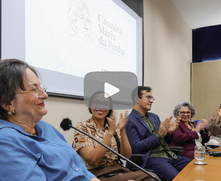 Pessoas sorrindo e batendo palmas para a ativista Maria da Penha