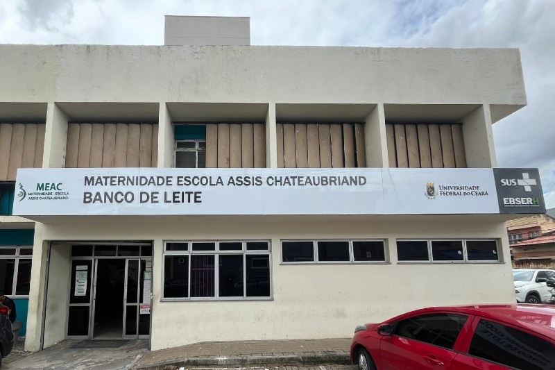 Fachada do Banco de Leite da Maternidade-Escola Assis Chateaubriand (MEAC-UFC), com identifica&ccedil;&atilde;o da unidade, logomarcas institucionais, portas de acesso e janelas do pr&eacute;dio.