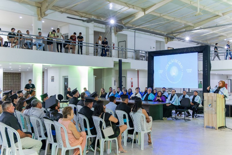 Colação de grau da UFC em Crateús, realizada em um espaço interno. Formandos, familiares e professores acompanham a cerimônia, marcada pela solenidade e celebração da conclusão da graduação.