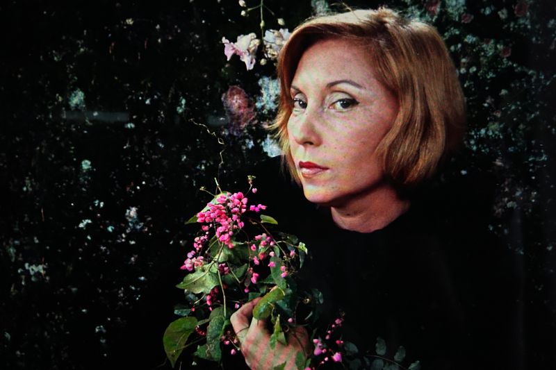 Clarice Lispector segurando flores com a m&atilde;o e olhando fixamente para a c&acirc;mera