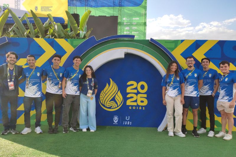 Painel do JUBs 2026 com estudantes abra&ccedil;ados lateralmente de um lado e do outro