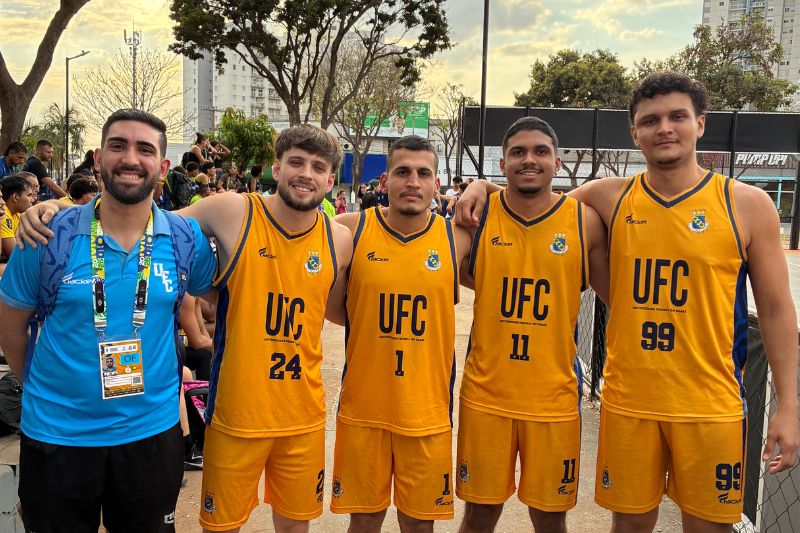 Quatro jogadores de basquete e um t&eacute;cnico abra&ccedil;ados lateralmente