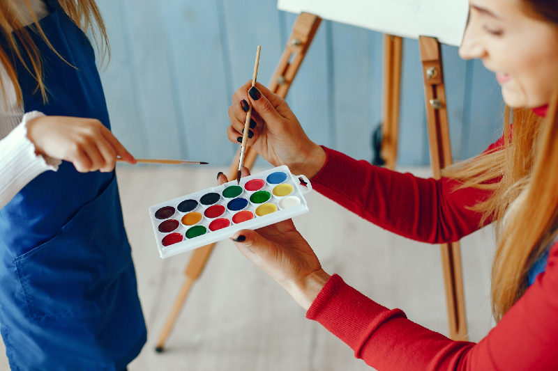 Mulher e criança pintando uma tela