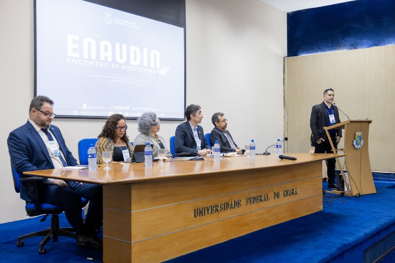 ntegrantes da mesa de abertura da 3&ordf; edi&ccedil;&atilde;o do ENAUDI &ndash; Encontro de Auditorias, realizado no Audit&oacute;rio da Reitoria da UFC. Ao fundo, painel com a identidade visual do evento.