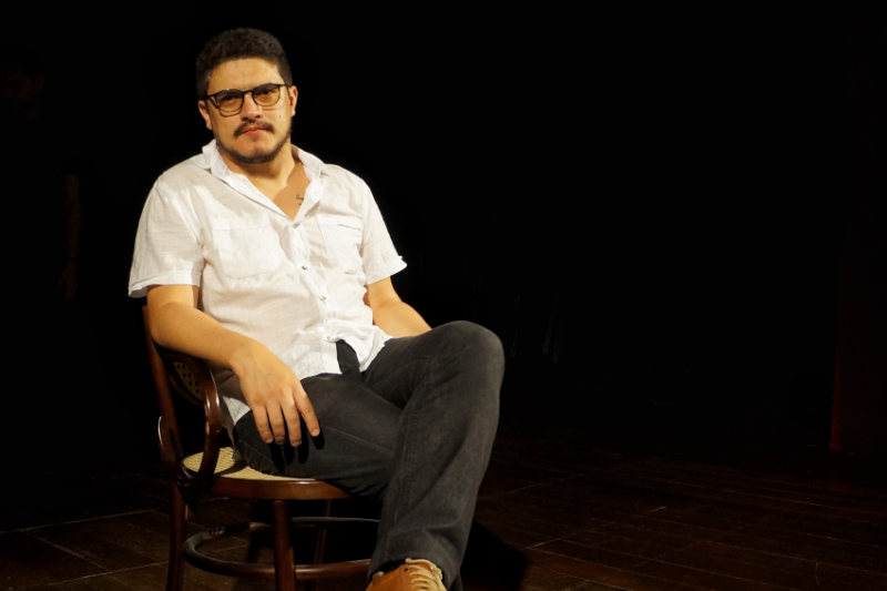 Foto do pesquisador L&eacute;o Mackellene sentado em cadeira, em fundo preto (Foto: Alana &Aacute;vila)