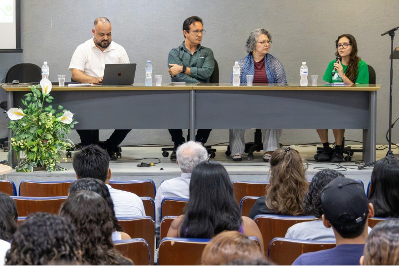 Quatro pessoas compondo mesa de abertura de evento na UFC, em auditório lotado