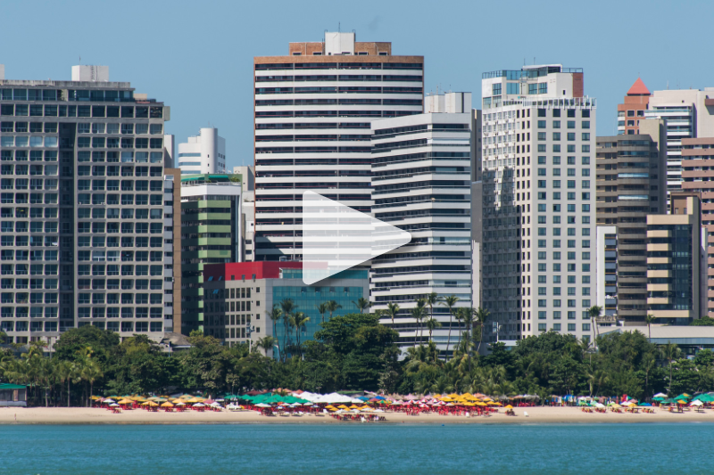 Orla de Fortaleza vista do mar com marca d'água de "play" para iniciar um vídeo