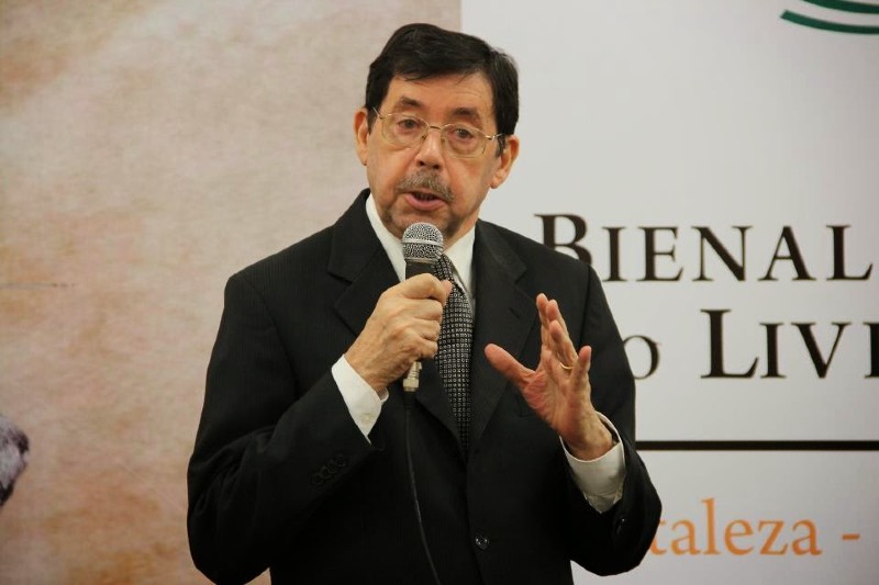 Imagem do professor Raimundo Falc&atilde;o, enquadramento da cintura para cima, professor fala ao microfone durante evento liter&aacute;rio