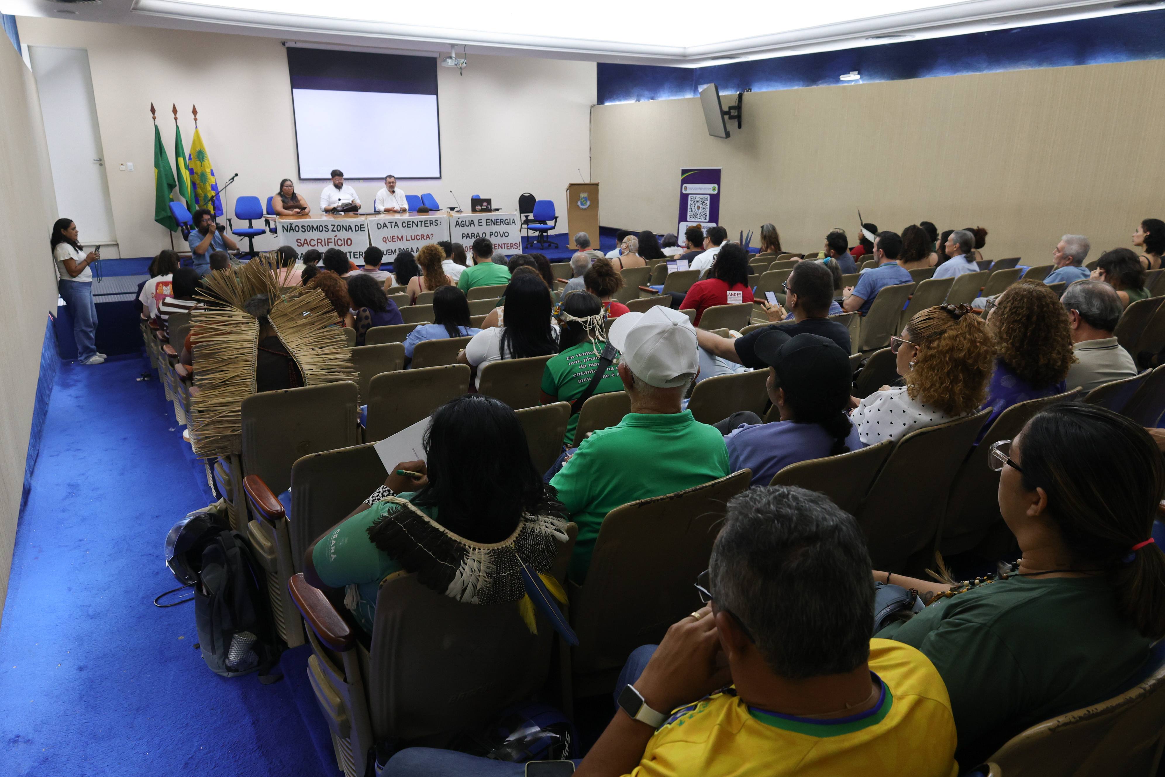 Pessoas sentadas no auditório da Reitoria ouvindo os convidados do debate