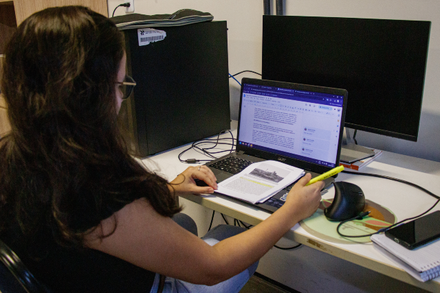 Mulher sentada em mesa digitando em laptop